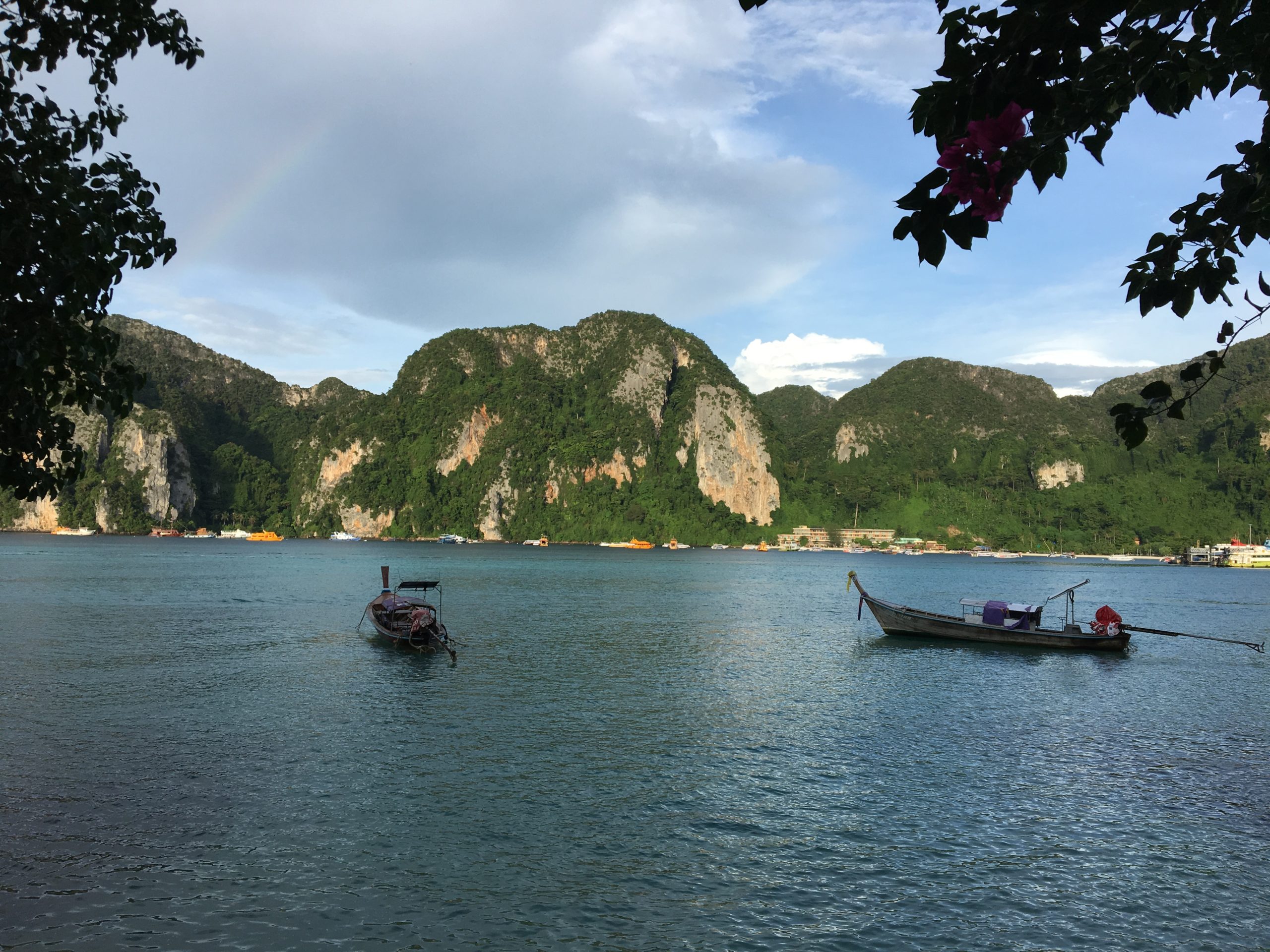 mar com montanhas ao fundo e dois barquinhos típicos da tailandia