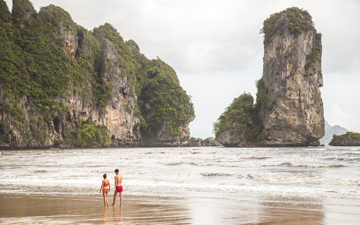 Um casal caminhando na praia de au nang