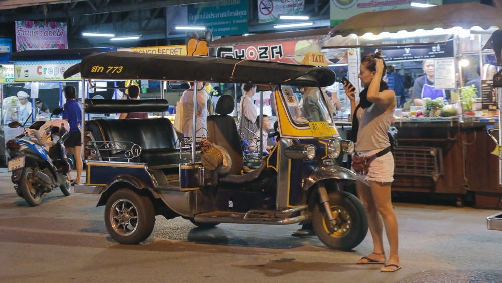Mulher parada em frente a um tuk tuk em chiang mai na tailândia