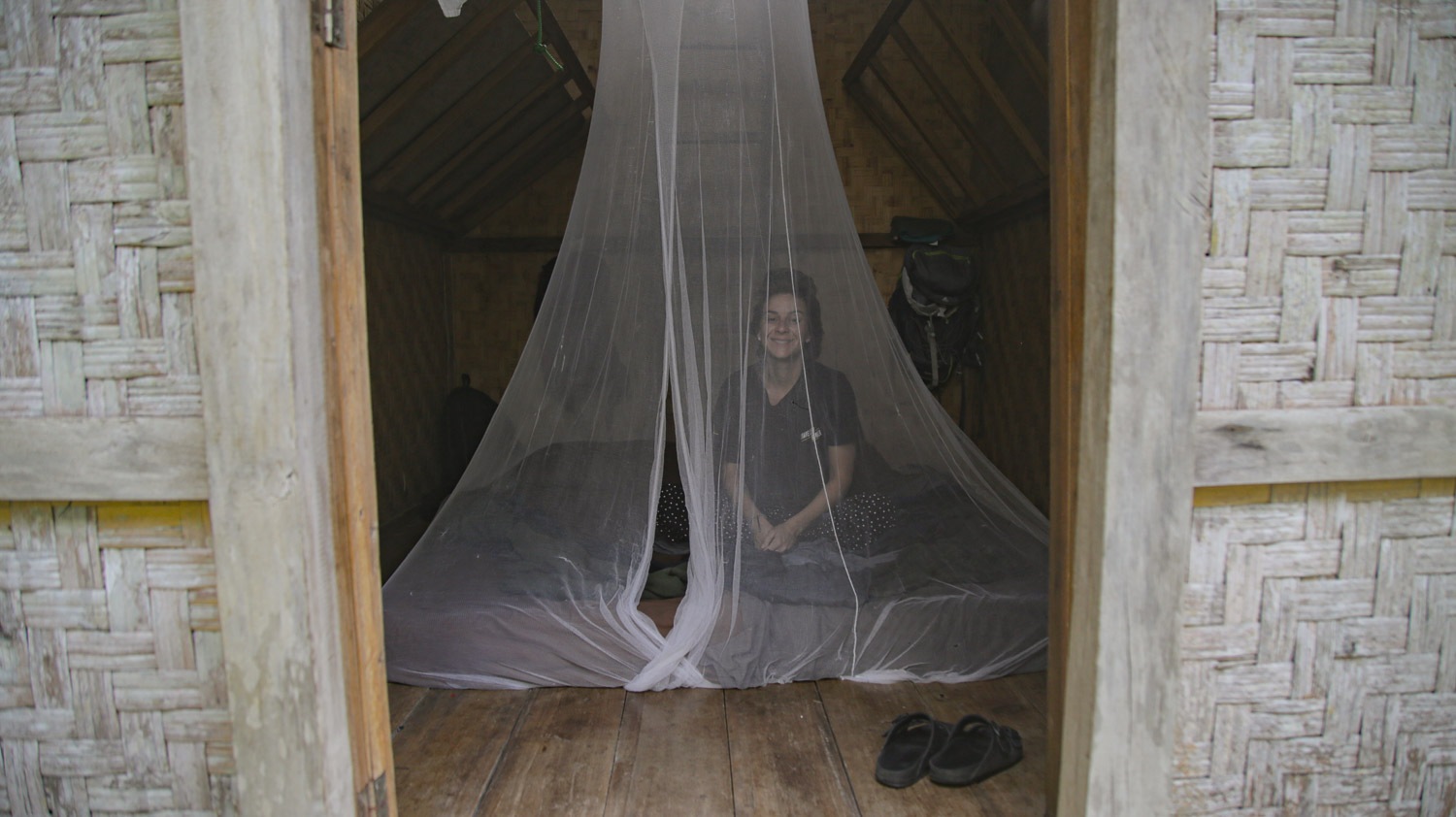 uma mulher dentro de uma cabana de madeira dentro de um mosquiteiro