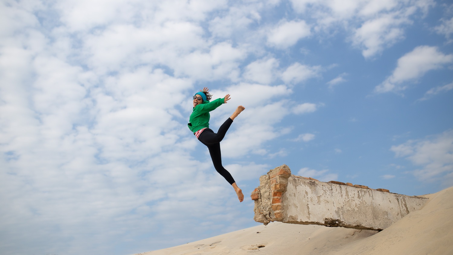 mulher saltando em uma duna de areia feliz