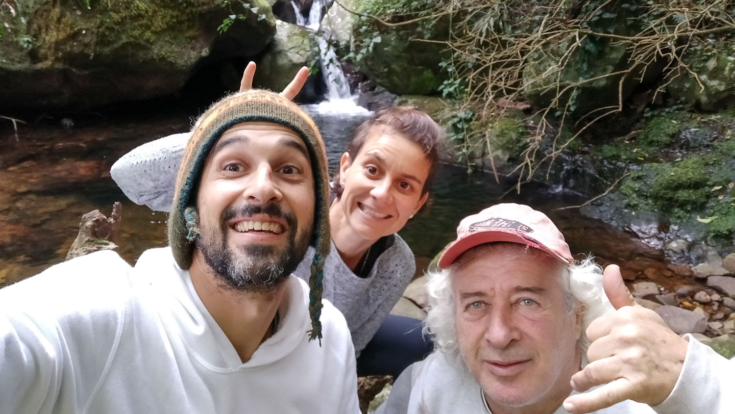 tres pessoas sorrindo e uma cachoeira no fundo