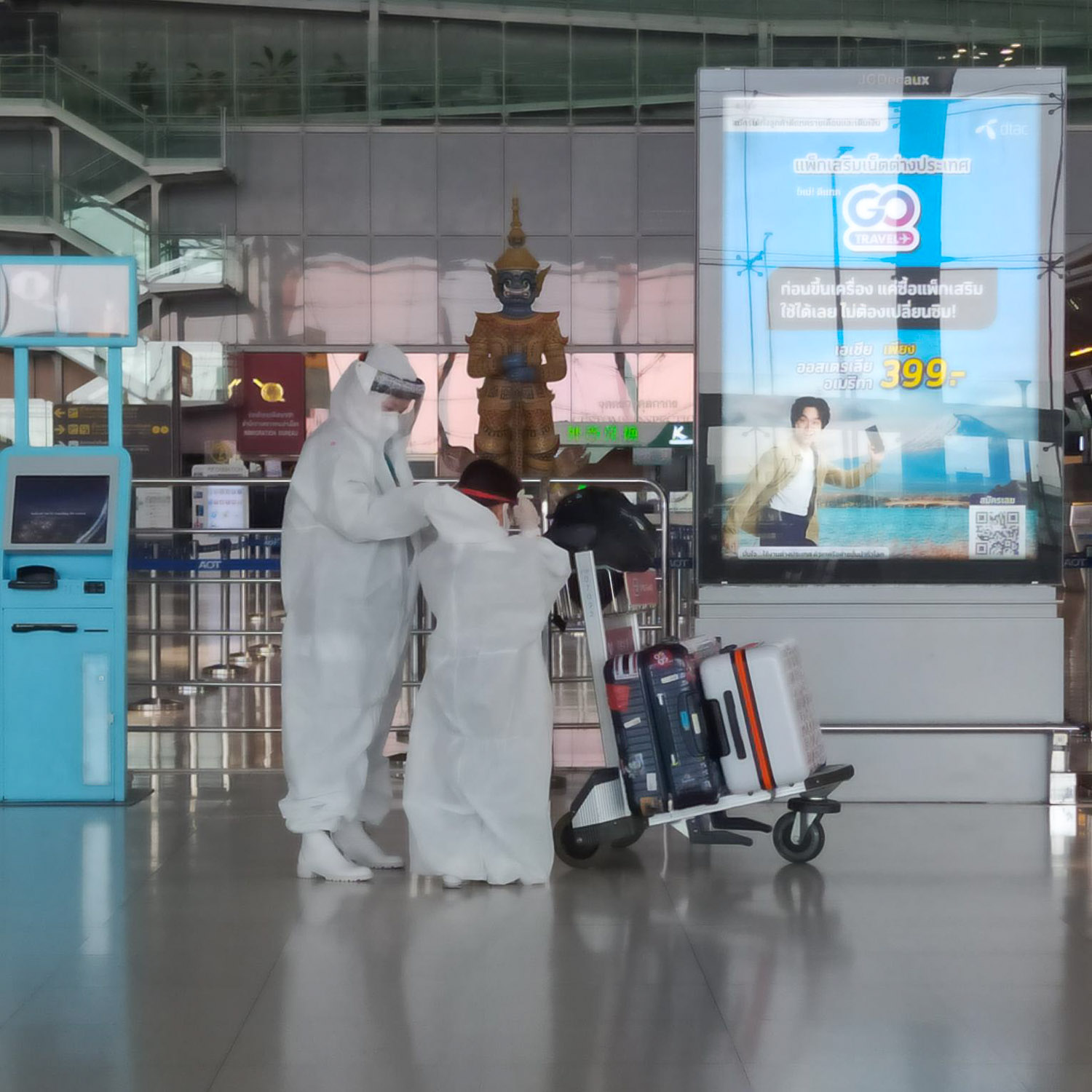 pessoas de macacão branco no aeroporto de bangkok durante covid 19