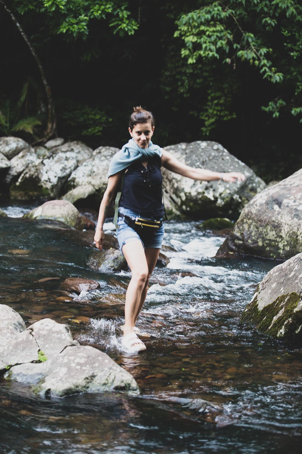 mulher atravessando um rio com os pés na agua