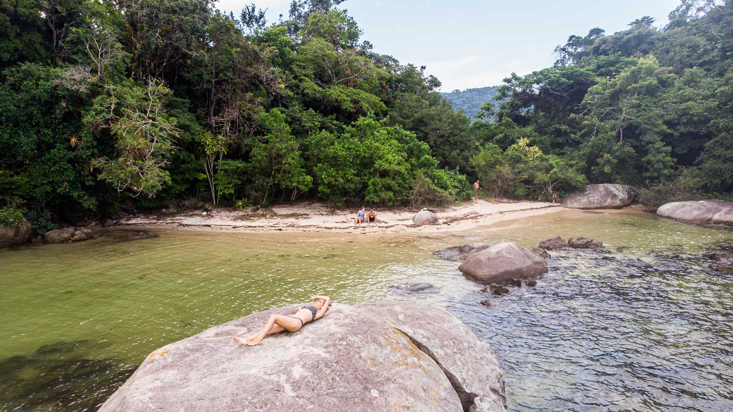 mulher deitada em uma pedra no mar