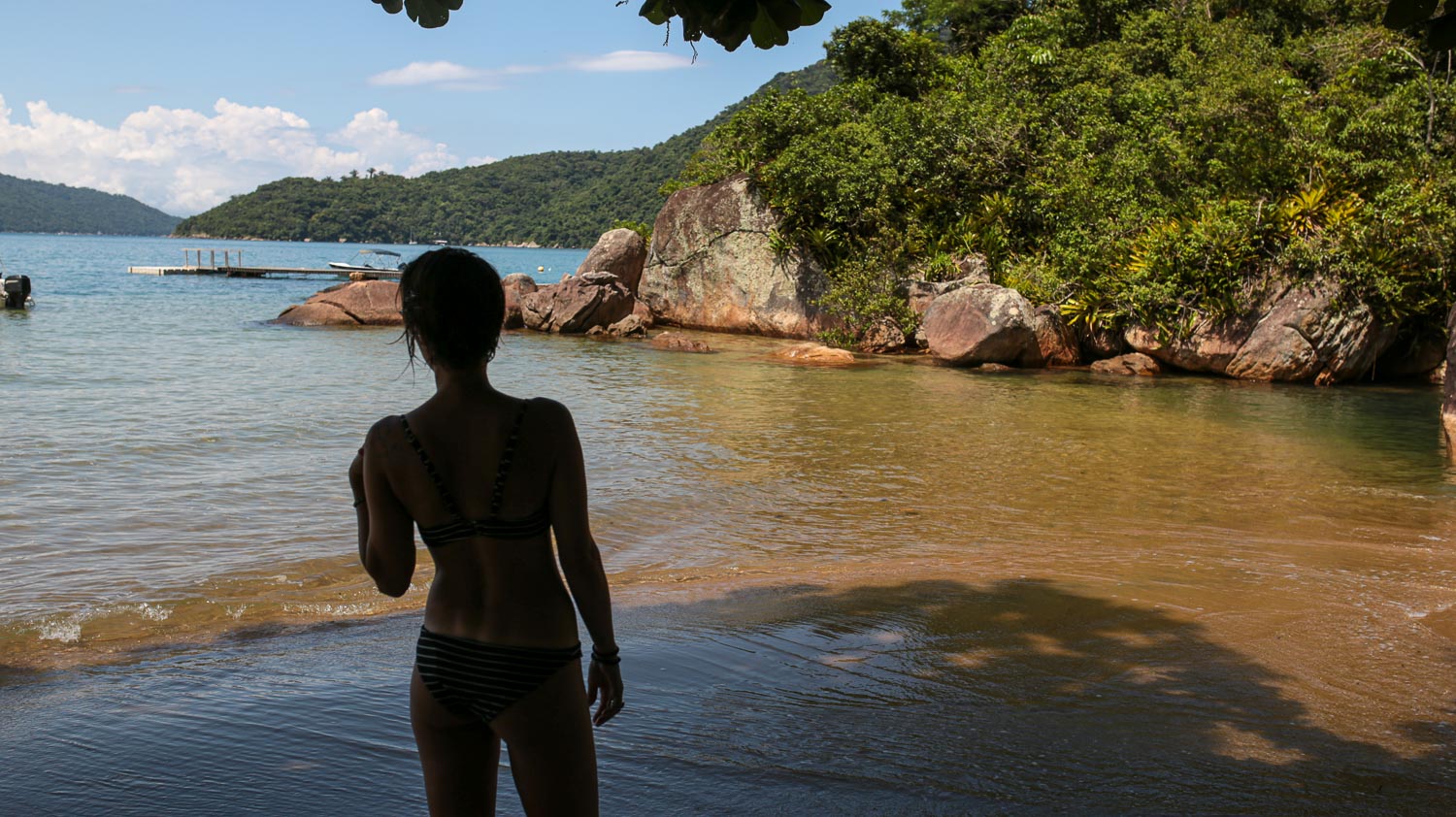 mulher debaixo de sombra de castanheiras na praia do engenho em paraty