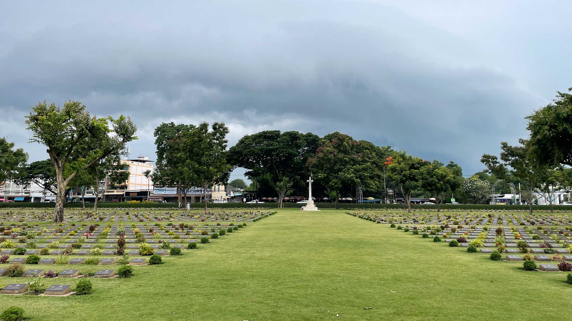 vista geral do cemitério de guerra com seus túmulos num gramado verde e com muitas flores e arvores ao fundo