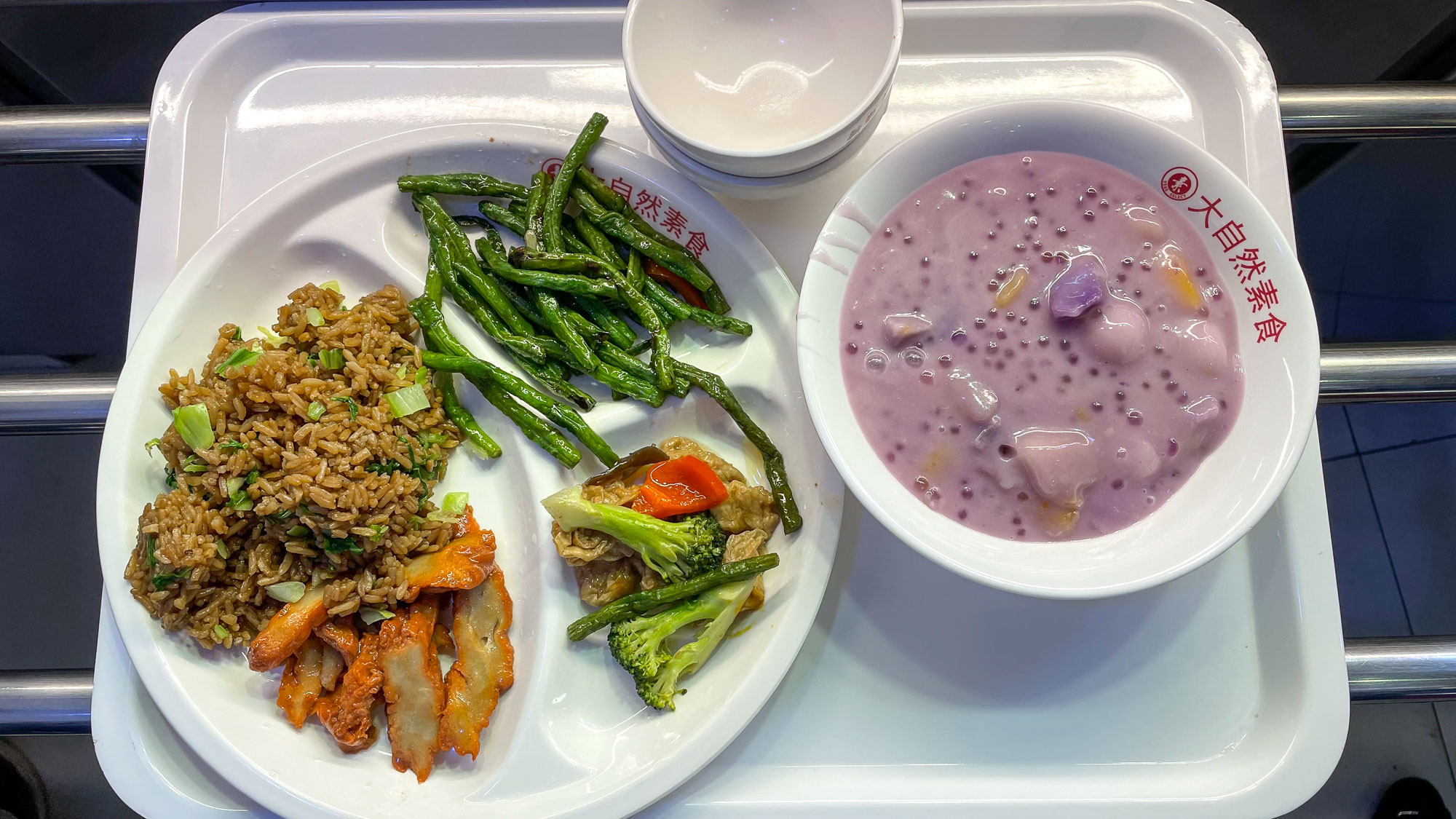 comida vegetariana chinesa, um prato com legumes e arroz e uma tigela com uma sobremesa roxa tipo mingau